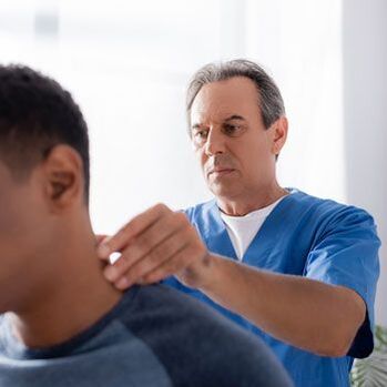 A doctor examines a patient with neck pain. 